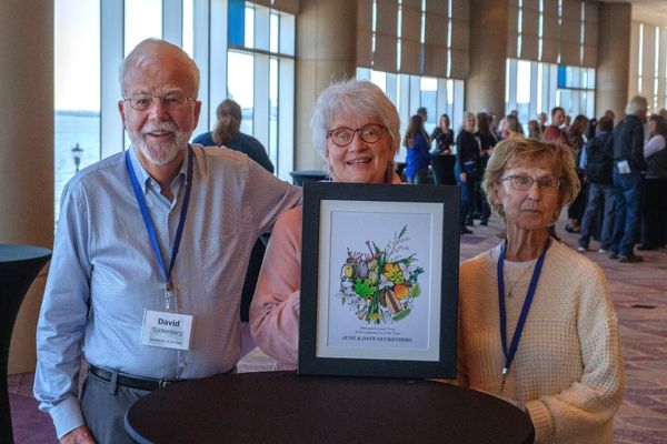 Three people pose for a photo holding a framed award