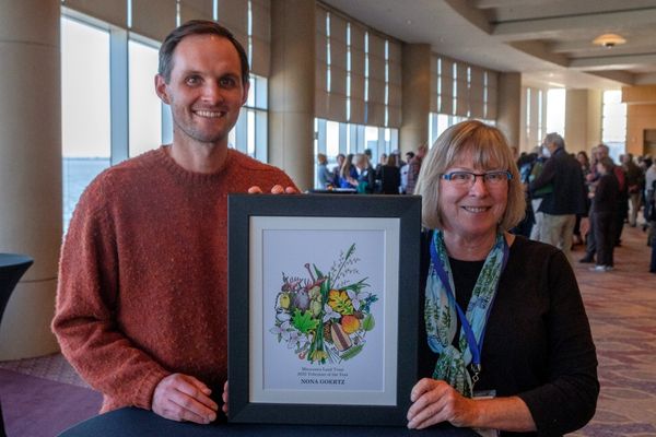 Two people pose for a photo holding a framed award