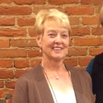 A woman with short blonde hair smiles towards the camera